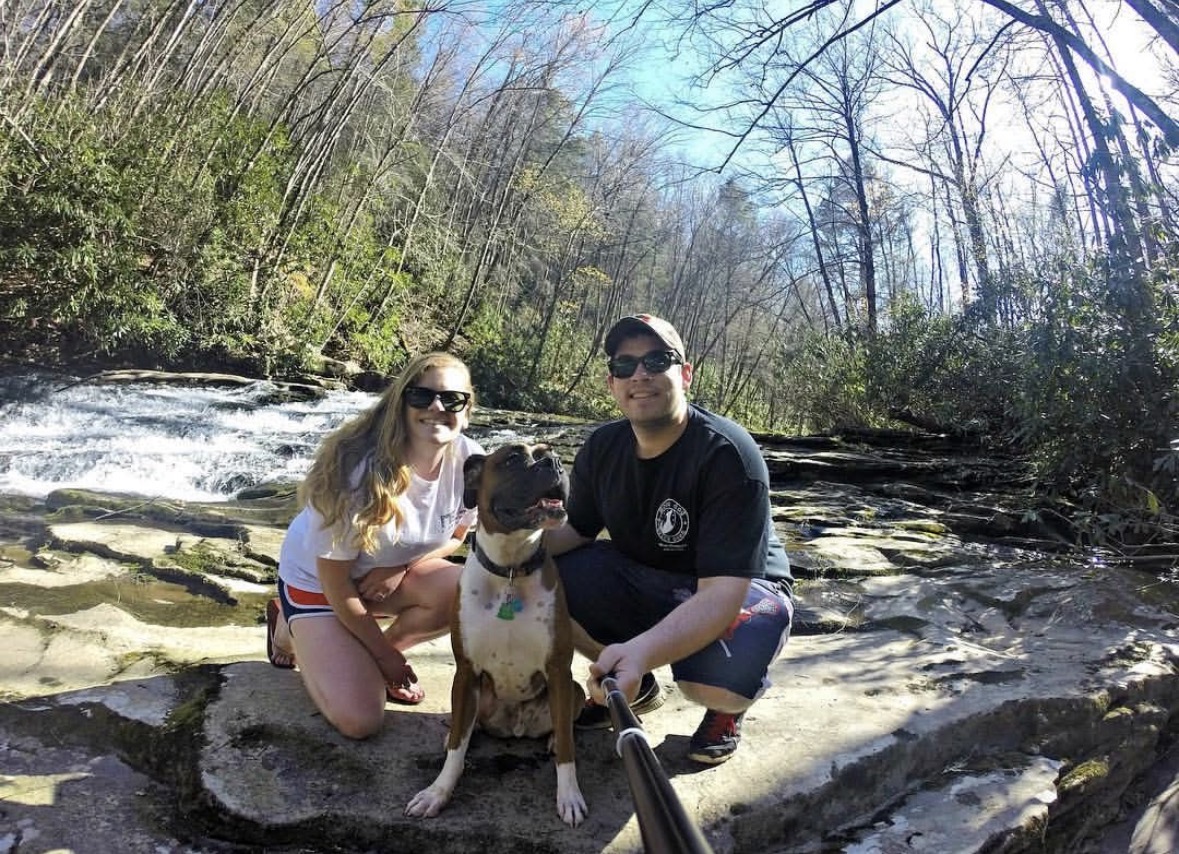 Katie and Christian crouched smiling with dog 