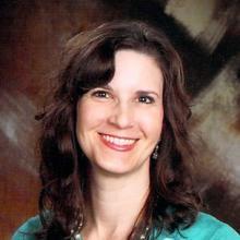 photo of smiling woman with dark hair wearing a green shirt