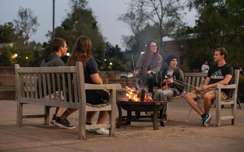 Students roasting marshmallows around a fire