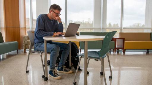 Student studying at table with laptop